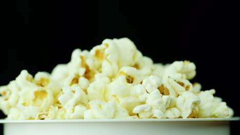 Ein-Glas-Popcorn-Auf-Schwarzem-Hintergrund-Dreht-Langsam-4k-Videos