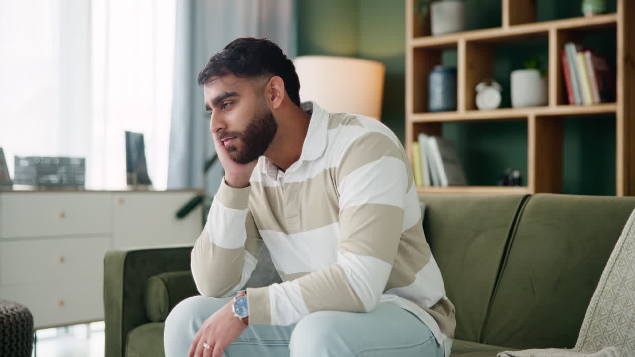 Sad man sitting on couch at home
