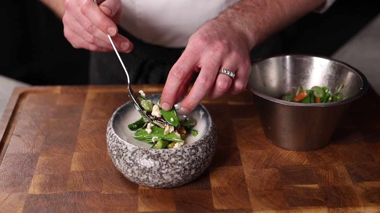 Chef dresseert verse groene groentesalade in restaurantkeuken