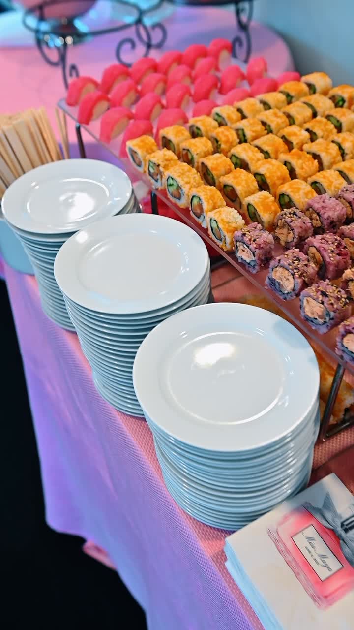 Roll di sushi misti e nigiri di salmone su tavolo da buffet per catering. File di roll di sushi colorati e nigiri di salmone serviti su alzatine di vetro con zenzero e wasabi.