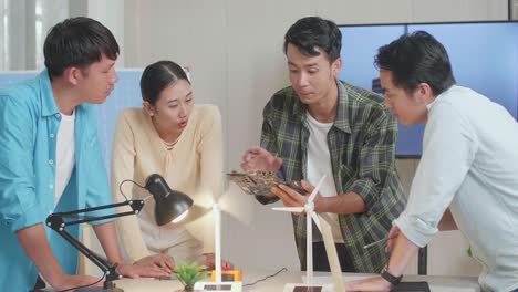 asian engineers group discussing about green circuit board while testing the wind turbine at the office