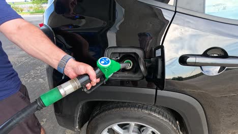 man refueling car at gas station