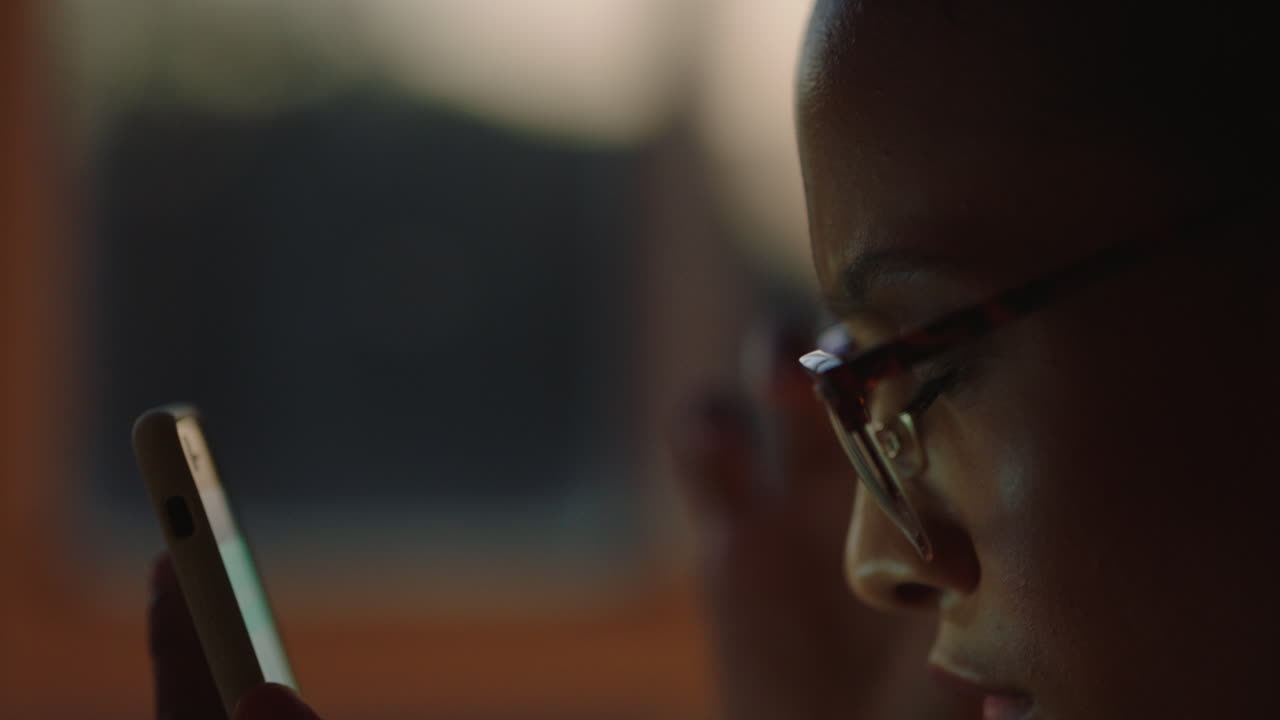 close up beautiful mixed race woman using smartphone browsing online reading positive messages online enjoying social media communication texting working late at night wearing glasses