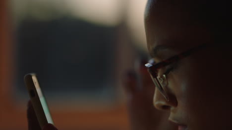 close up beautiful mixed race woman using smartphone browsing online reading positive messages online enjoying social media communication texting working late at night wearing glasses