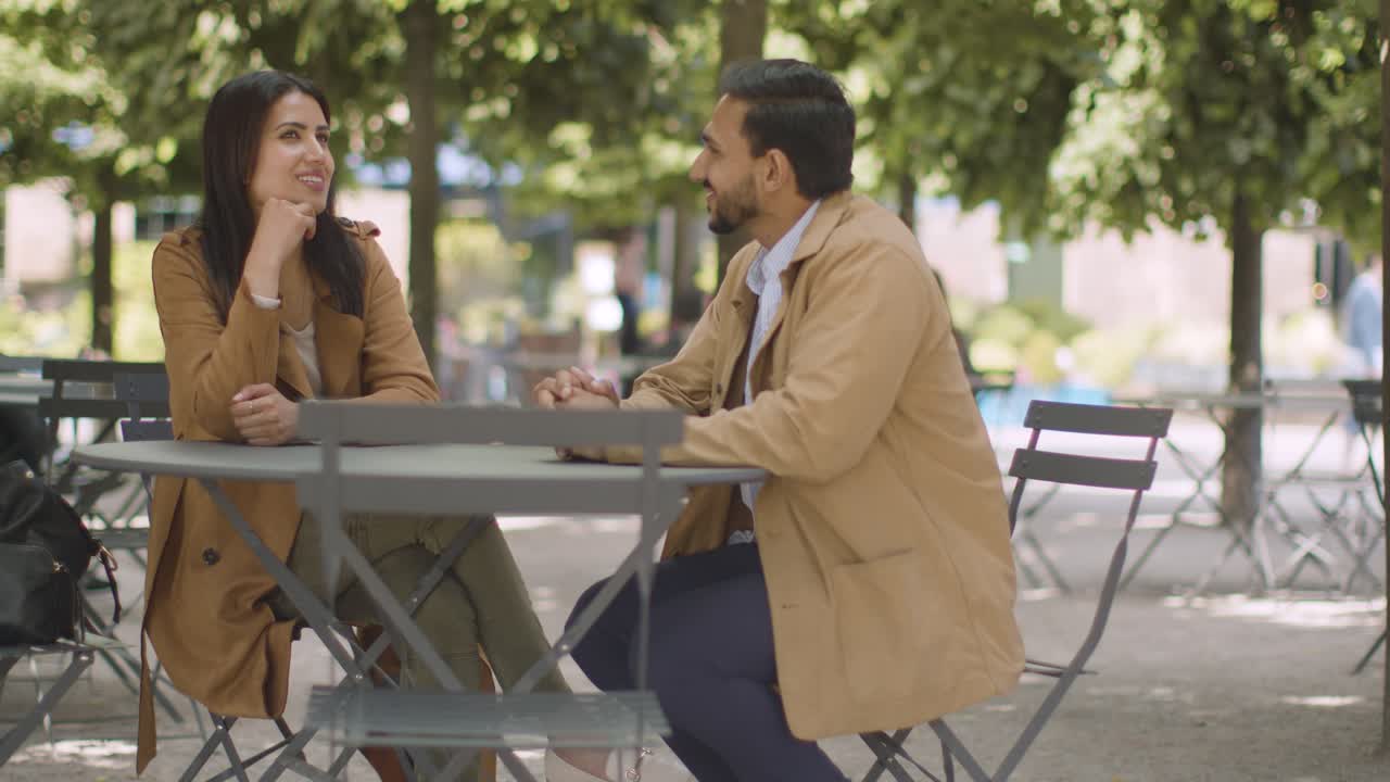 pareja musulmana en una cita sentada en una mesa al aire libre en la calle de la ciudad hablando juntos 1