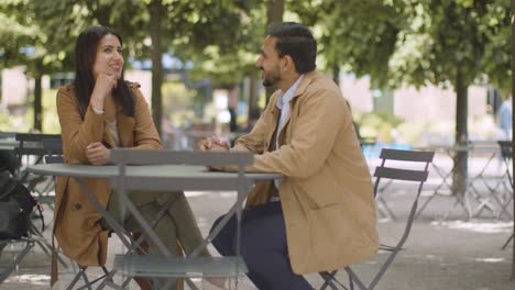 Muslim-Couple-On-Date-Sitting-At-Outdoor-Table-On-City-Street-Talking-Together-1