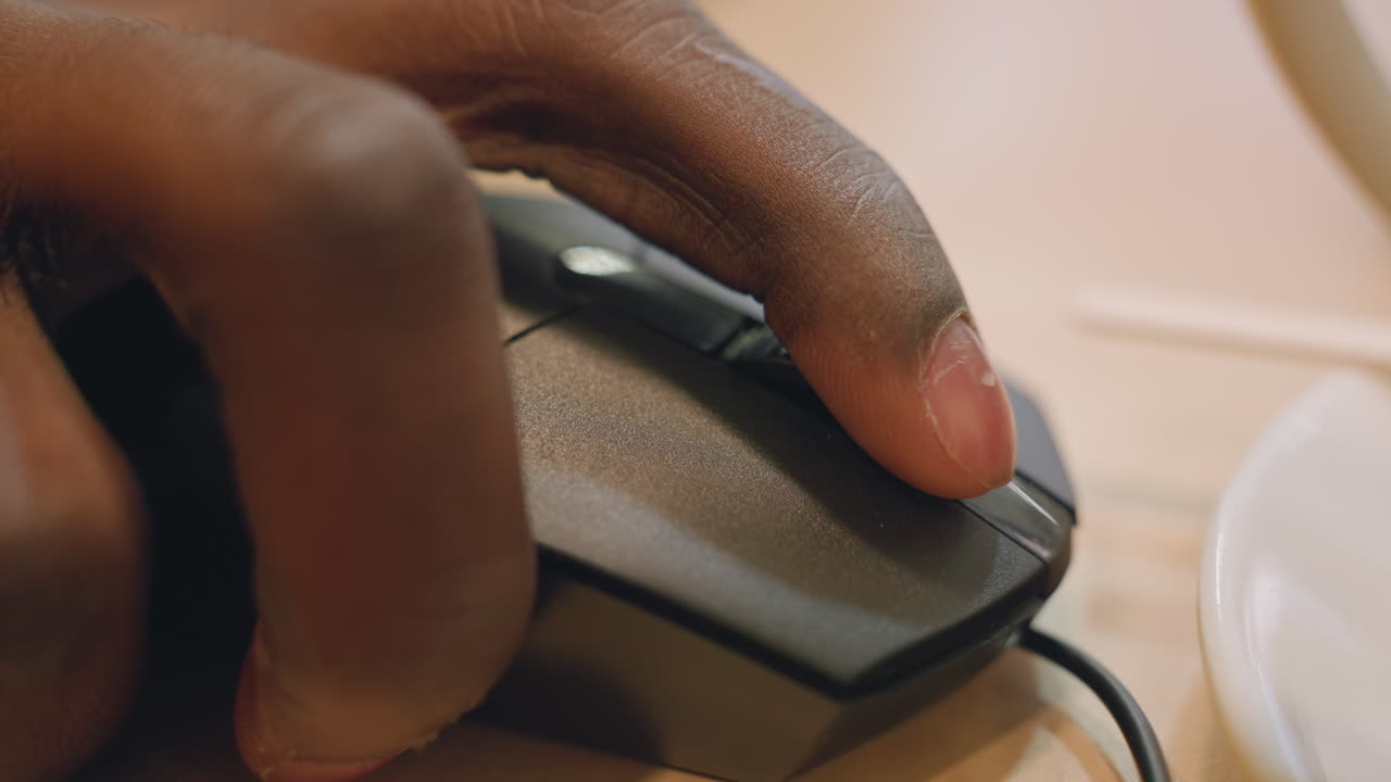 Focused work environment. Developer intensely engaging with computer. Closeup of hand operating mouse with concentration. Detailed view of hand clicking mouse in bright office setting