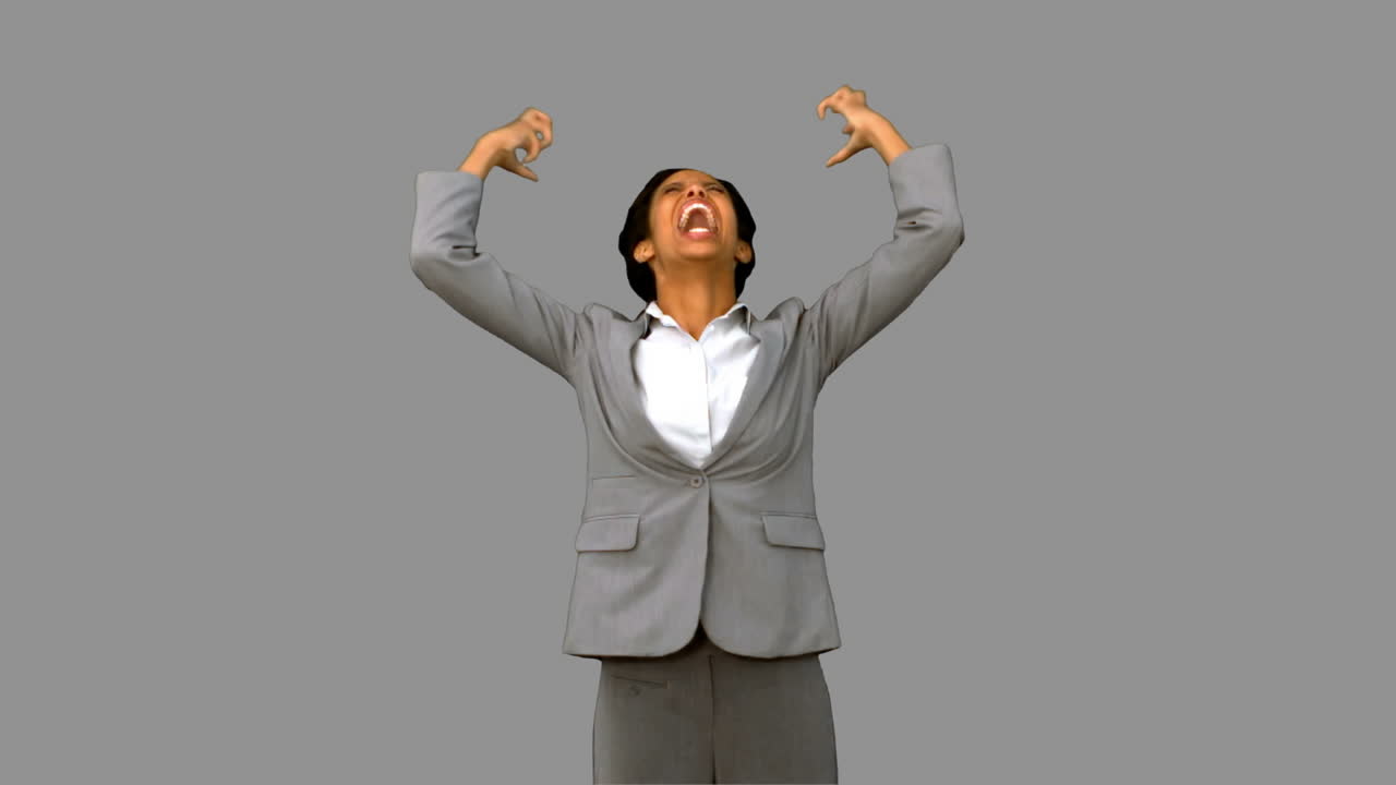 화가 난 사업가 여성이 회색 스크린에서 팔을 들어 올리고 있습니다.