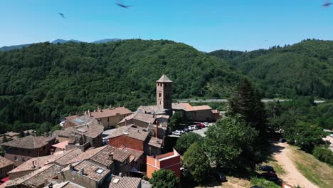 aerial drone fly above espinelves spanish comarca countryside summer landscape, old cathedral architecture and valley of green trees uphill