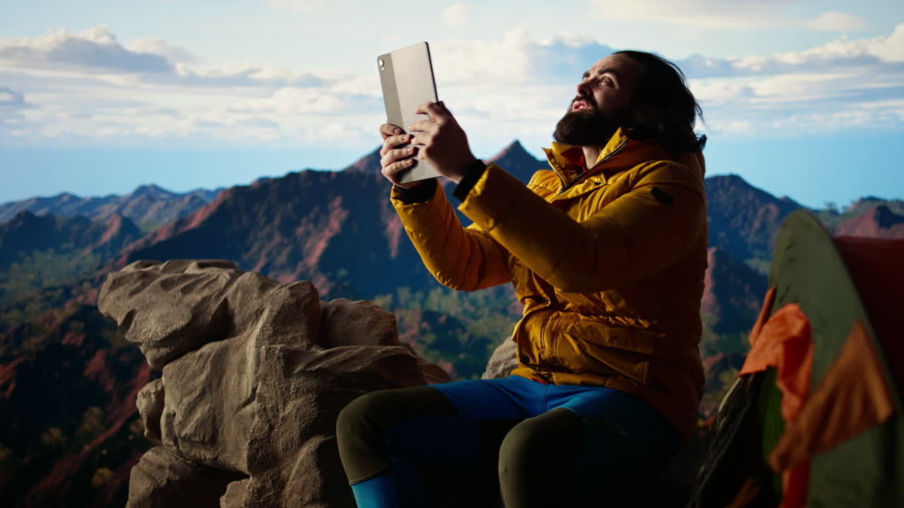 campista luchando contra el viento fuerte mientras usa la tableta en el campamento de gran altitud