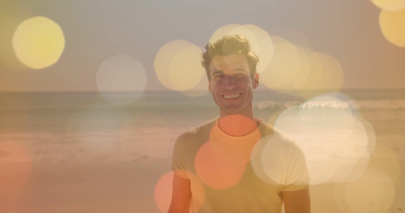 Man standing on beach, camera pushing in, bokeh overlays shifting over sea, smiling for marketing