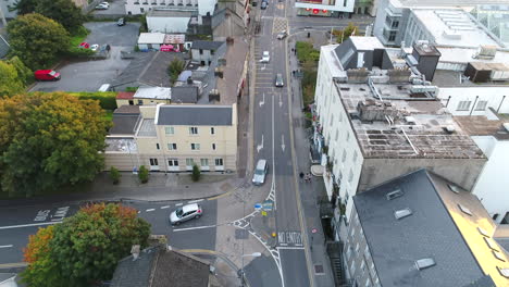 drone shot moving up from overhead bustling city street to sunset skyline over galway, ireland