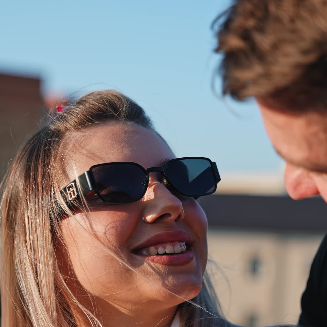 Kaukasisch stel staat samen buiten. De man kust zijn vrouw die een zonnebril draagt. Verticaal scherm. Close-up
