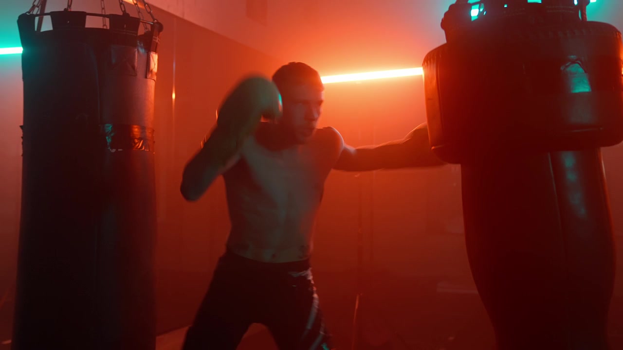 Homem Treinando com Saco de Pancadas em Academia Escura com Luzes Neon