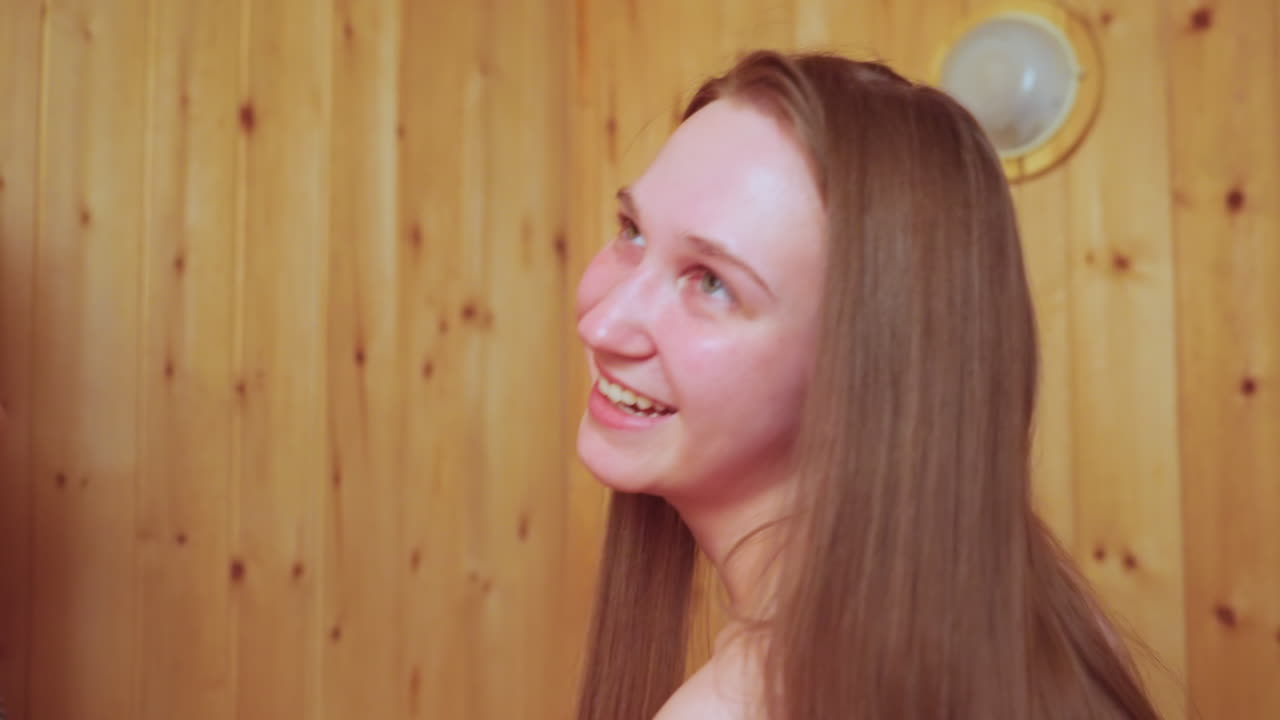 close up of young woman smiling and gazing upward in wooden sauna interior steam haze and warm glow highlighting healthy skin calm expressive eyes relaxed joyful moment in spa wellness ritual