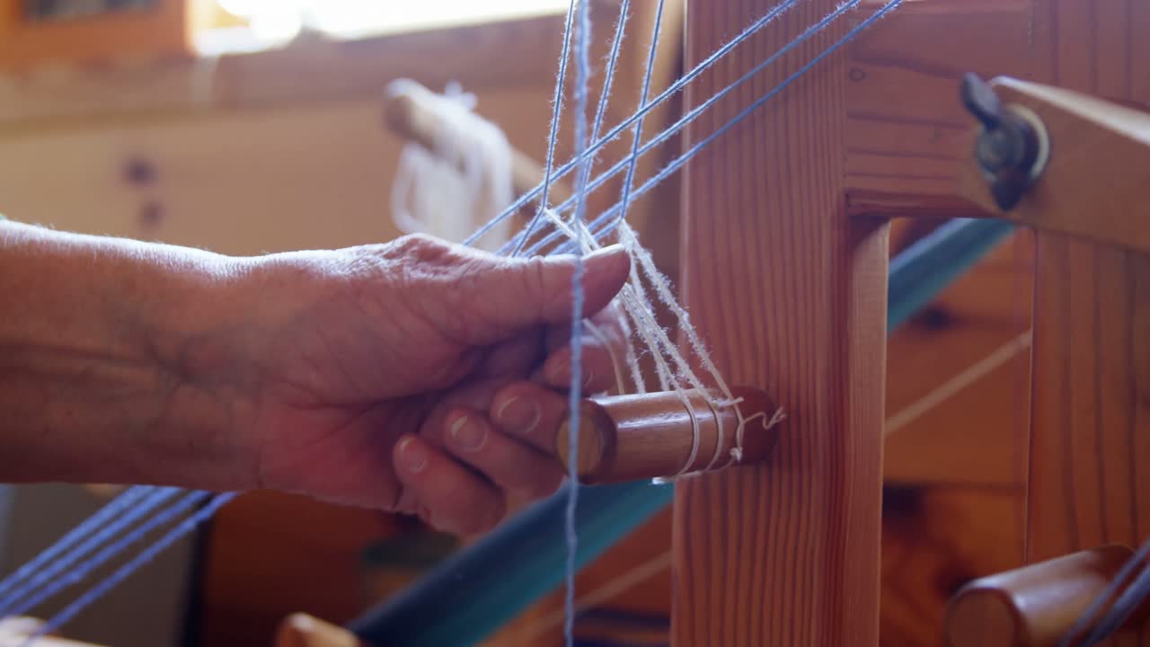 mujer mayor colocando hilo de lana en la máquina de tejer 4k