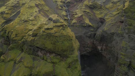 Un-Dron-En-Cascada-Disparó-Mientras-El-Agua-Caía-Agresivamente-Sobre-Una-Cornisa-Rocosa-De-Color-Amarillo-Verdoso-En-Una-Piscina-De-Inmersión-Debajo