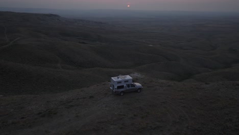 truck with camper overlooking vast prairie landscape at dusk with soft light fading