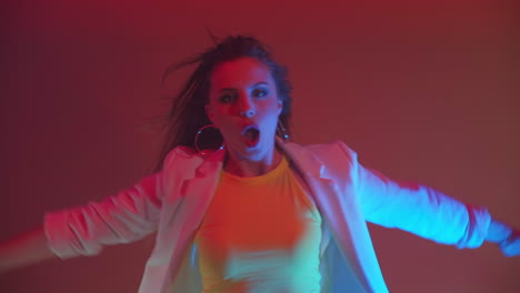 An-incendiary-young-beautiful-woman-dances-sings-and-looks-at-the-camera-in-the-light-of-spotlights-colored-neons-and-flashing-lights