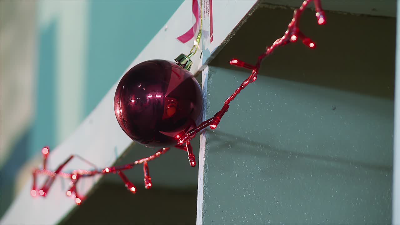 una cadena de luces de navidad y una joya roja en un estante de madera. cerca. enfoque pan. resolución 4k.