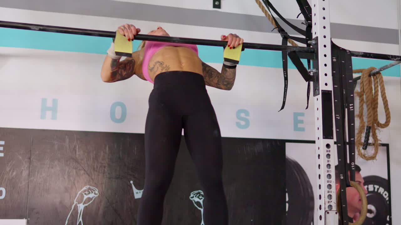 Stærk kvinde laver pull-ups på en stang i et fitnesscenter