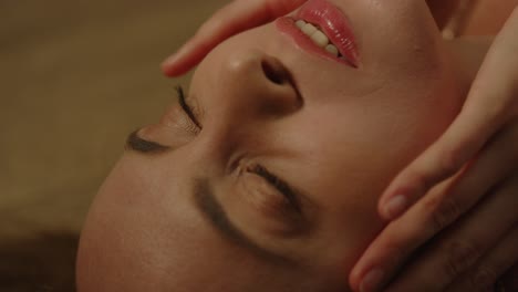 beautiful close up of an attractive woman lying on the floor with hands sensually caressing her face in slow motion