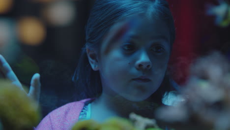 cute little girl in aquarium looking at fish curious child watching colorful sea life swimming in tank learning about marine animals in underwater ecosystem inquisitive kid at oceanarium