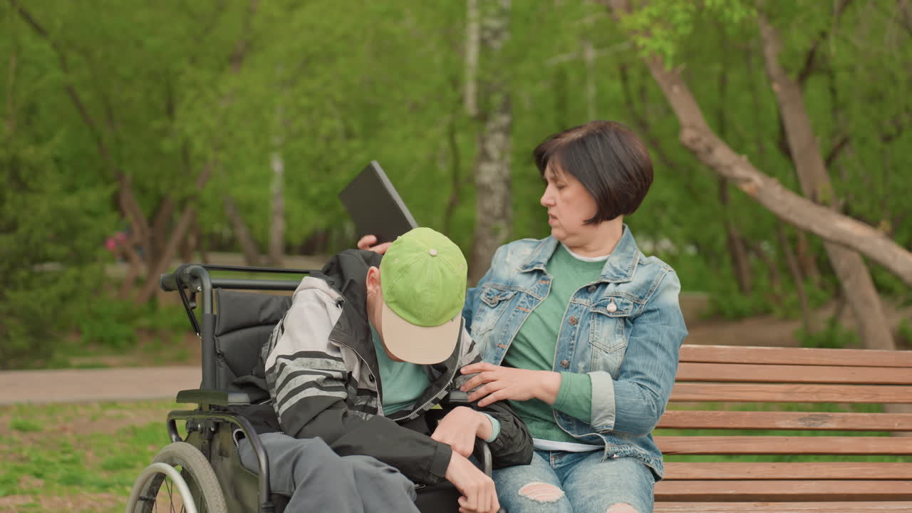 Helping Youth With Disabilities Outside, Mentor Instructing Young Man In Wheelchair Peacefully Outdoors, Supportive Caregiver Aiding Young Individual With Mobility Device In Calm Park Environment