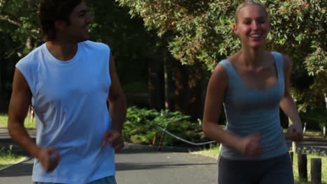 una pareja sonriente se mira mientras corren