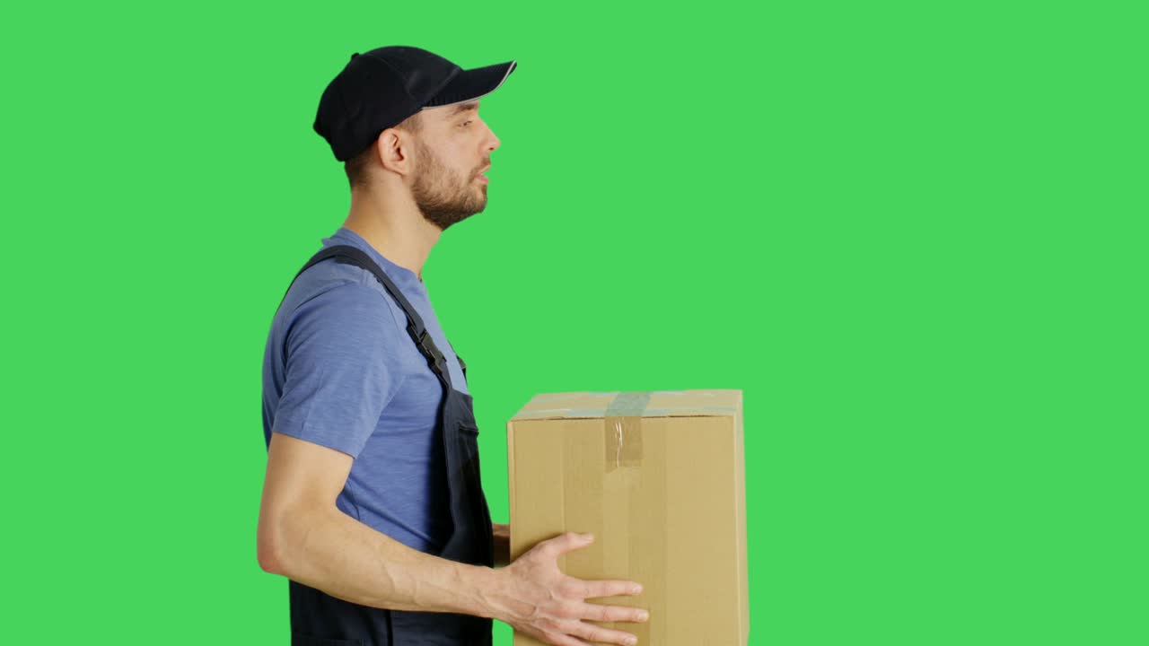 Profile Mid Shot of a Handsome Loader Handing in Cardboard Box. Shot with Green Screen Background.