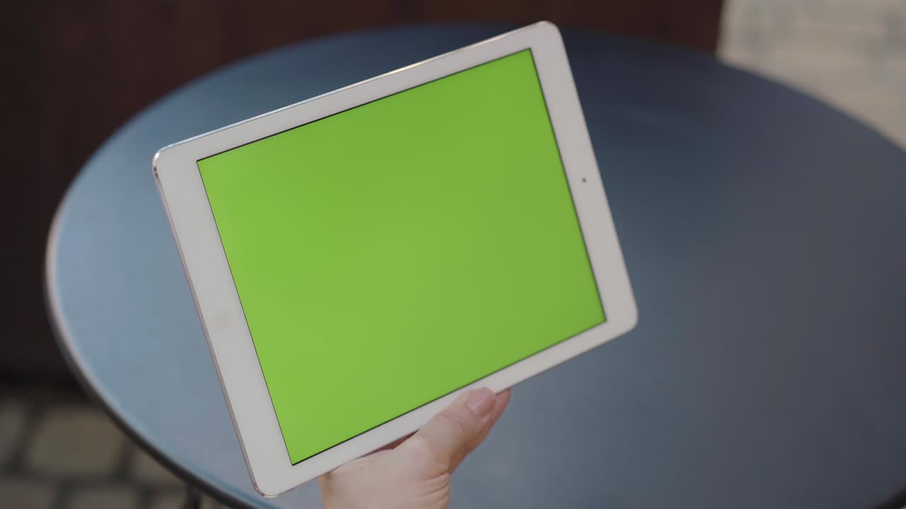 primer plano de la pantalla verde de la tableta en manos caucásicas femeninas. mujer irreconocible usando redes sociales o aplicaciones o navegando por internet y bebiendo café al aire libre. estilo de vida moderno.