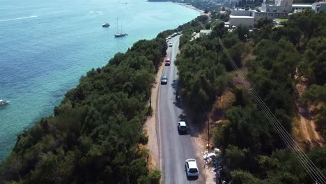 aerial following shot of moving motorbikes and cars on the coastline road