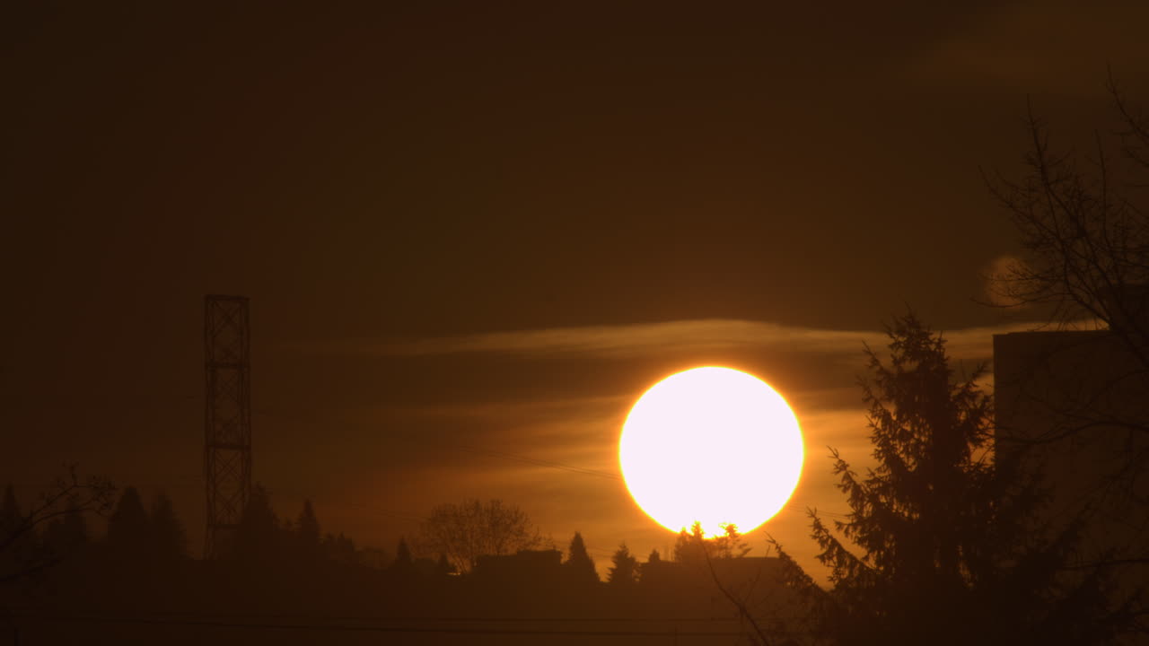 яркое солнце медленно поднимается вверх, просвечивая сквозь облака на рассвете - статичный кадр