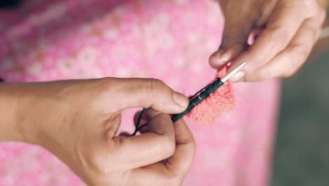 close up of knit work tie-up hand work woman siting and knitting with red and black wool