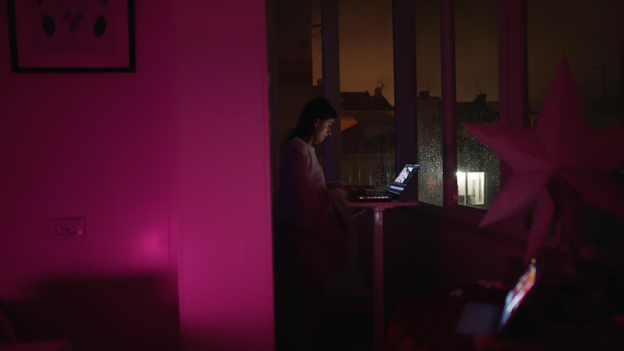 Donna che lavora al portatile di notte vicino alla finestra