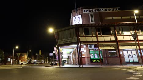 cars passing by an old, illuminated building at night