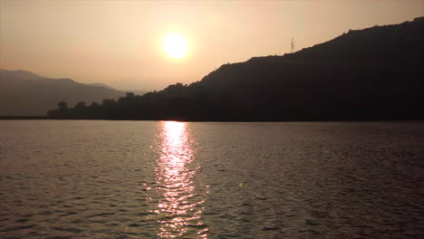 La-Puesta-De-Sol-En-Un-Lago-Y-Su-Reflejo-En-Tonos-Dorados-En-Aguas-Tranquilas-Es-Tentador,-Con-Un-Hermoso-Cielo-De-Tonos-Dorados-Como-Telón-De-Fondo