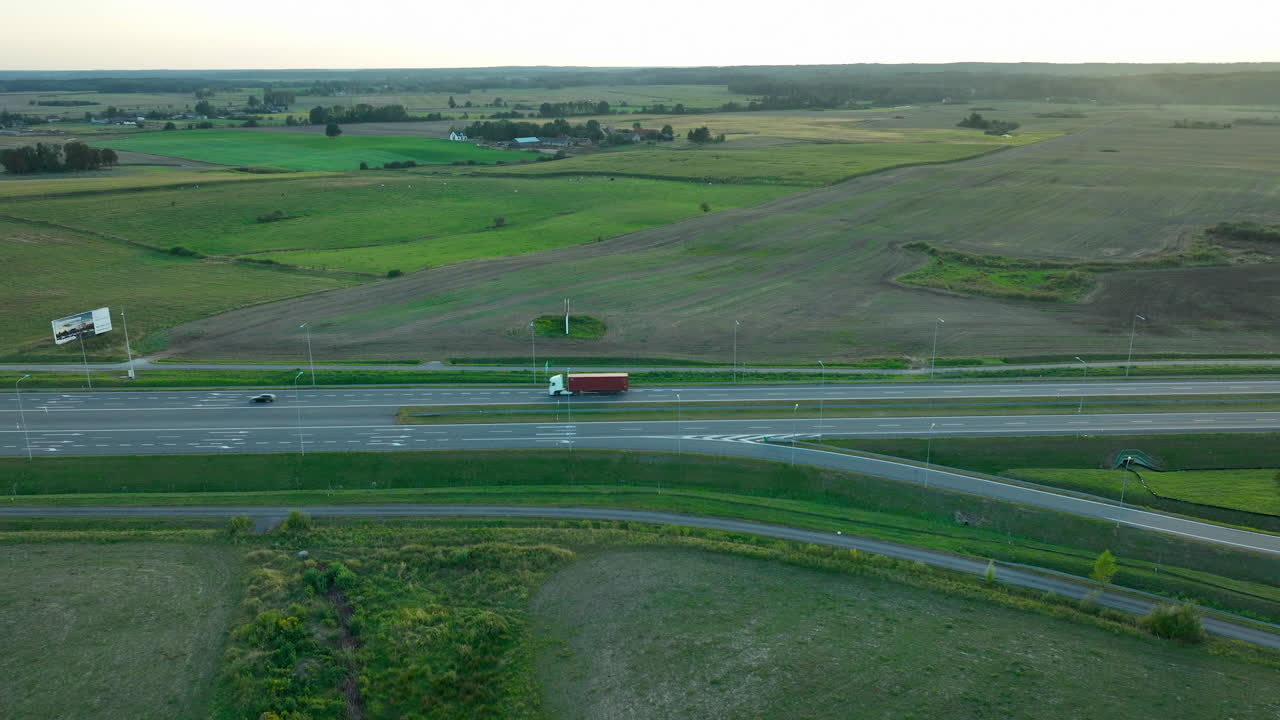 폴란드 시골 고속도로의 공중 촬영, 주변 농장과 움직이는 차량, 가는 태양의 부드러운 빛 아래