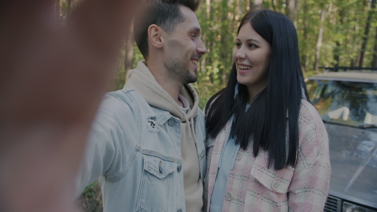 Couple taking a selfie in a forest near a car