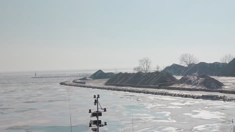 Drone-shot-of-a-frozen-harbour-and-stone-quarry-along-the-coastline-of-Canada-in-the-middle-of-winter