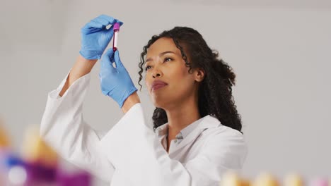 Video-of-biracial-female-doctor-holding-test-tube-on-blue-background