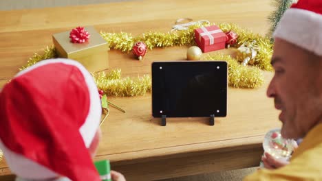 padre y dos hijos teniendo una videollamada en una tableta digital con espacio de copia durante la navidad