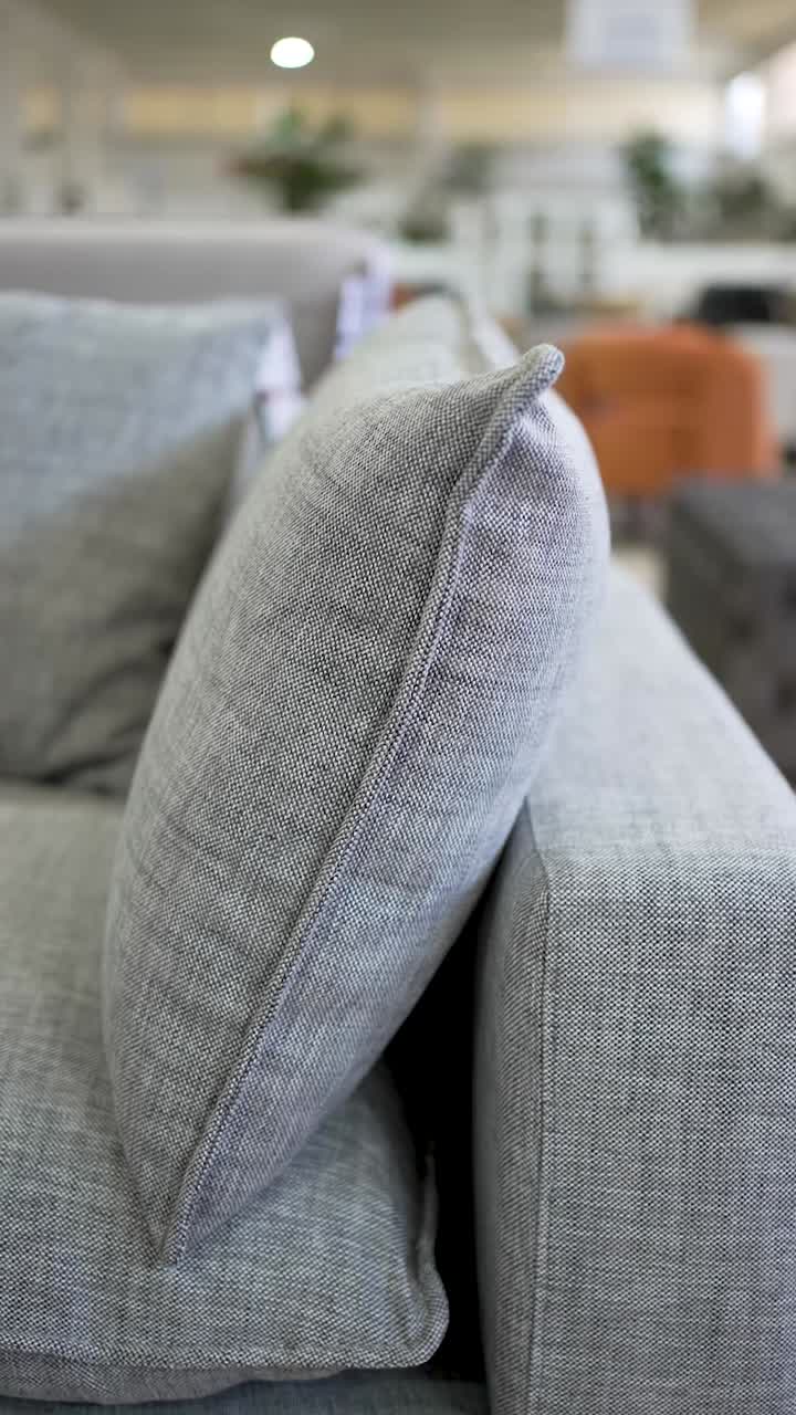 This clip showcases a contemporary sofa featuring plush cushions and sleek lines. Set in a bright showroom, it highlights the furniture's elegant design and comfort