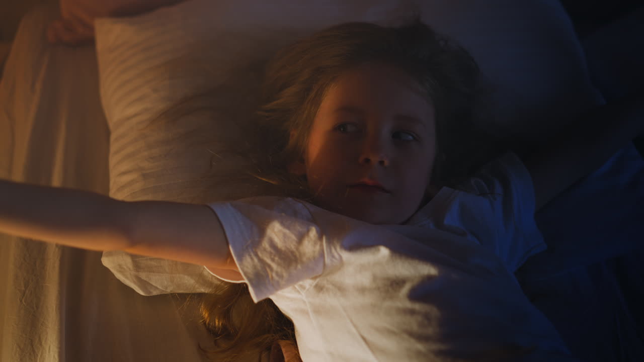 재미있는 작은 소녀는 밤에 편안한 침대에  ⁇ 어 있습니다.