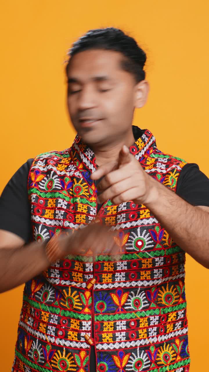 Pria dengan Rompi Warna-warni Menunjuk dan Memberi Isyarat dengan Ceria