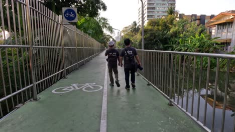 two people walking across a green bridge