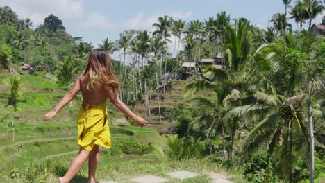 woman in yellow dress exploring lush rice terraces and palm trees in bali