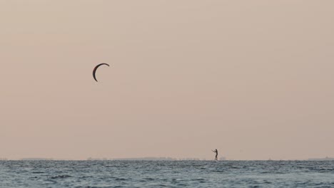 Kitesurfista-Solitario-Navegando-Con-Vientos-Suaves,-Bajo-La-Luz-Dorada-Del-Atardecer