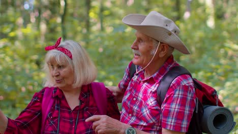 Senior-old-grandmother-grandfather-tourists-enjoying-walking,-hiking-with-backpacks-in-summer-wood