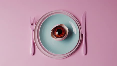 surreal eyeball in cracked egg on pastel plate